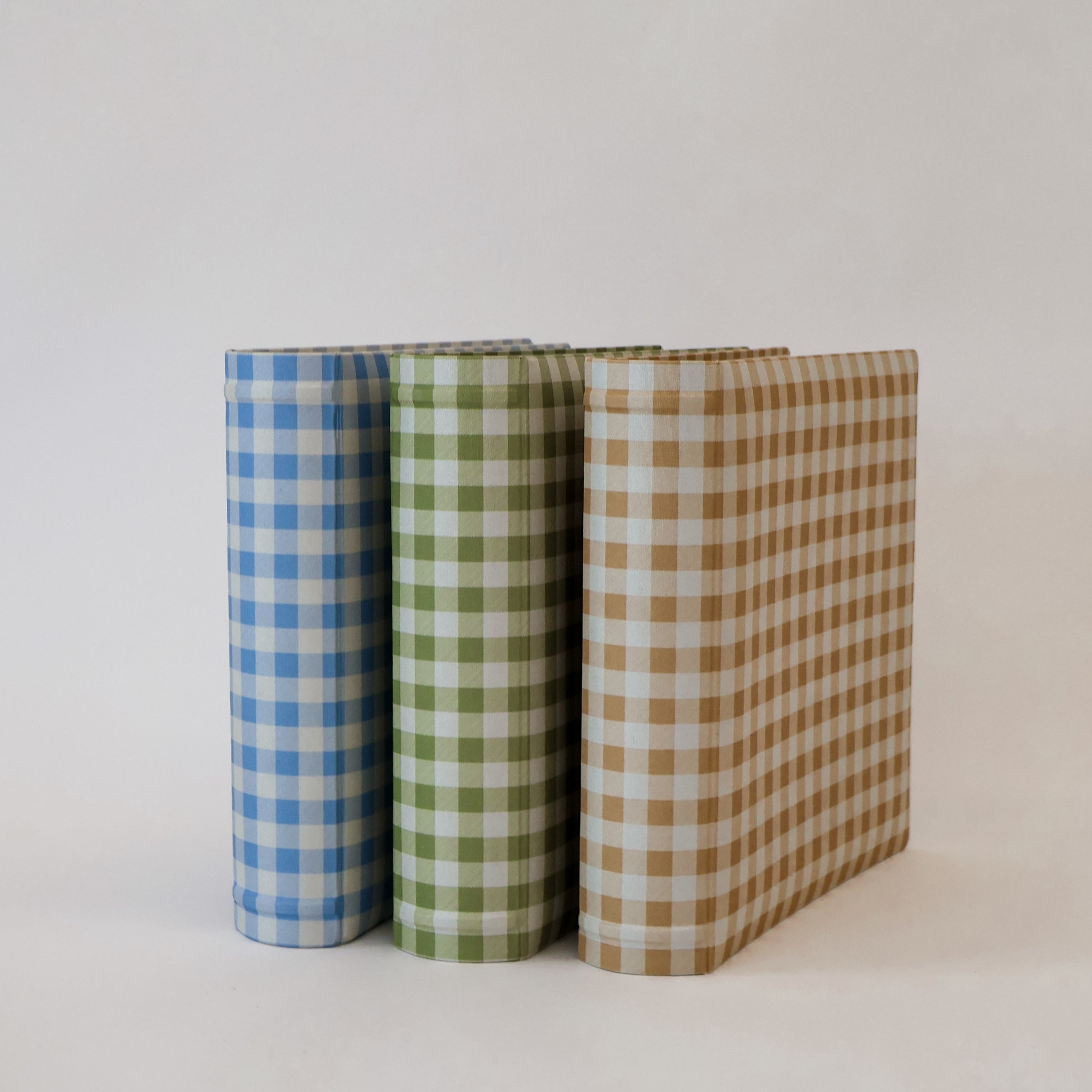 Three checkered scrapbook albums in blue, green, and brown on a white background