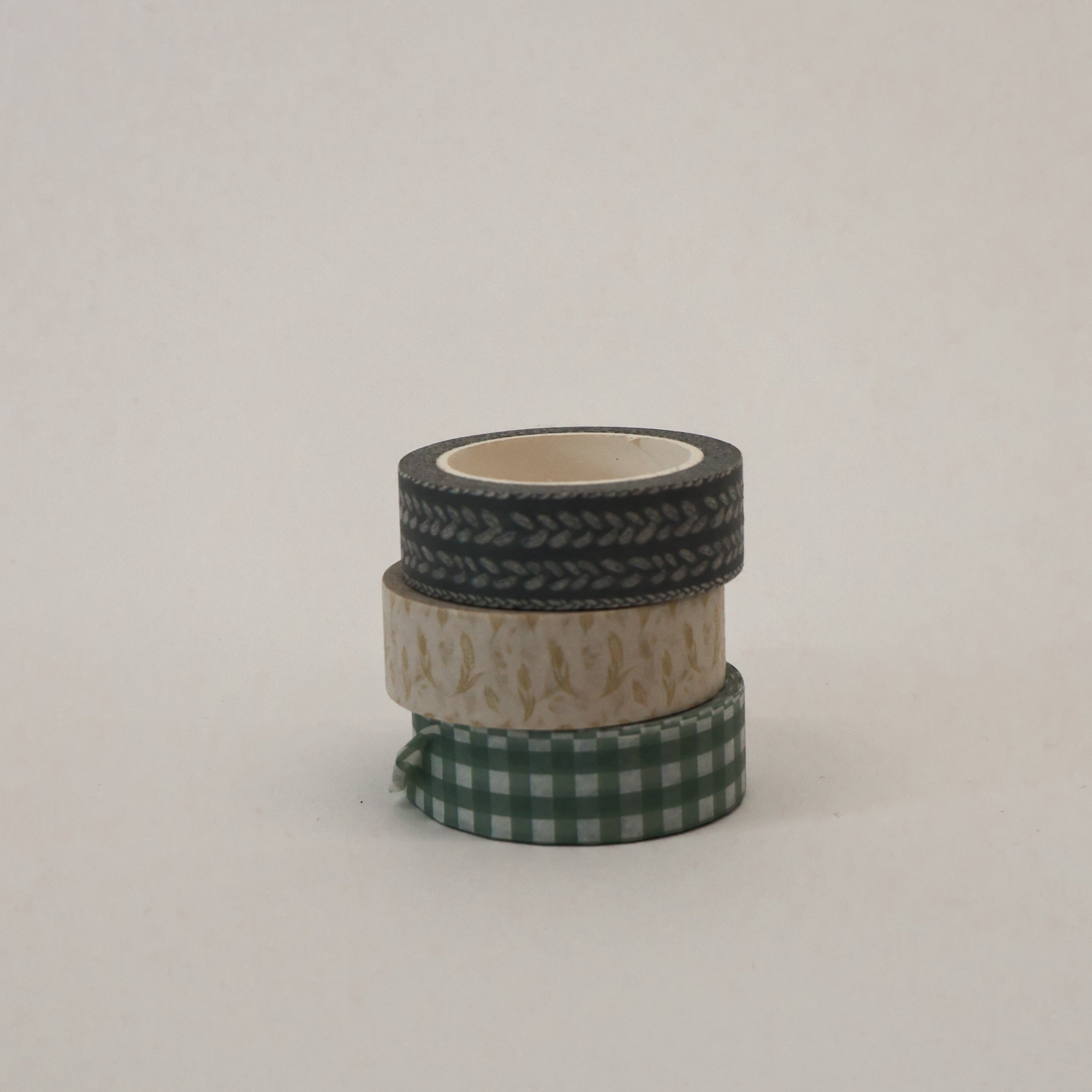 three rolls of washi tape with different patterns stacked on a light gray background